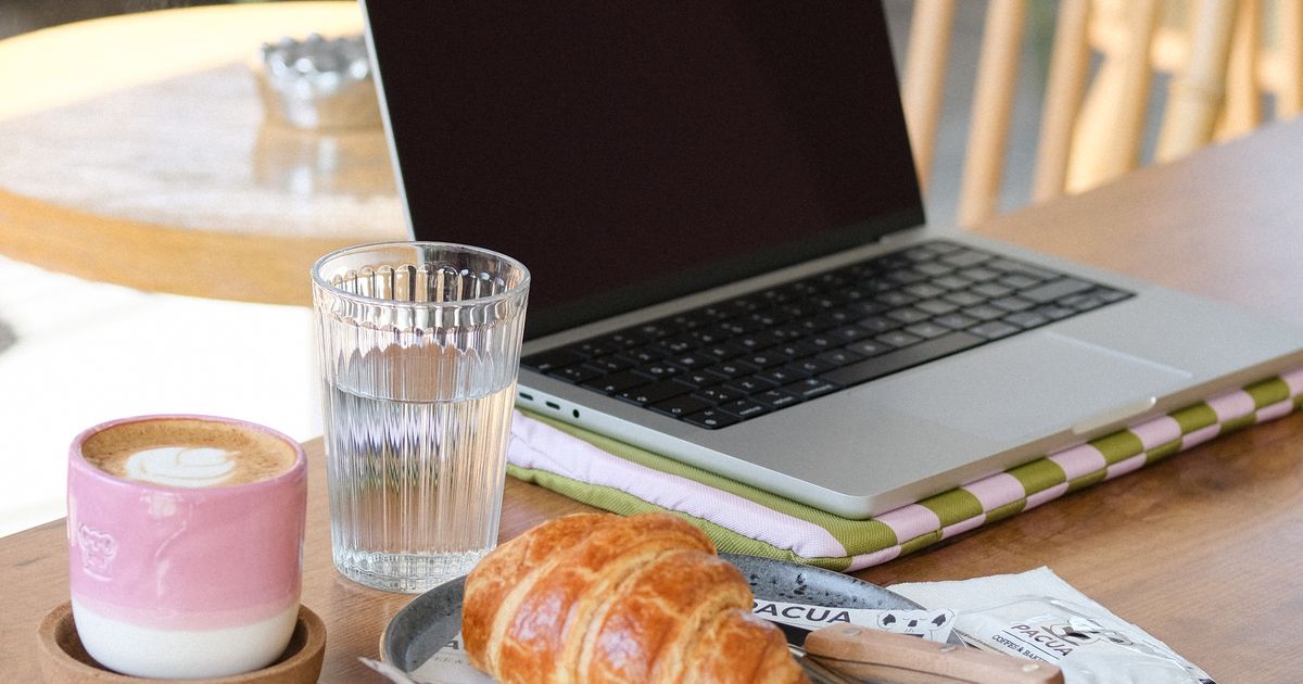 Founder working at a cozy café workspace with laptop and coffee, planning a product launch strategy