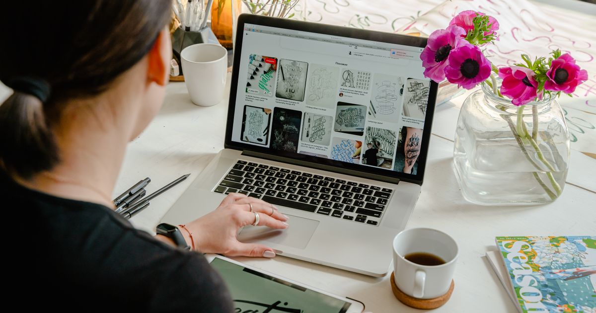 Designer using a laptop and tablet to produce brand and ad creative