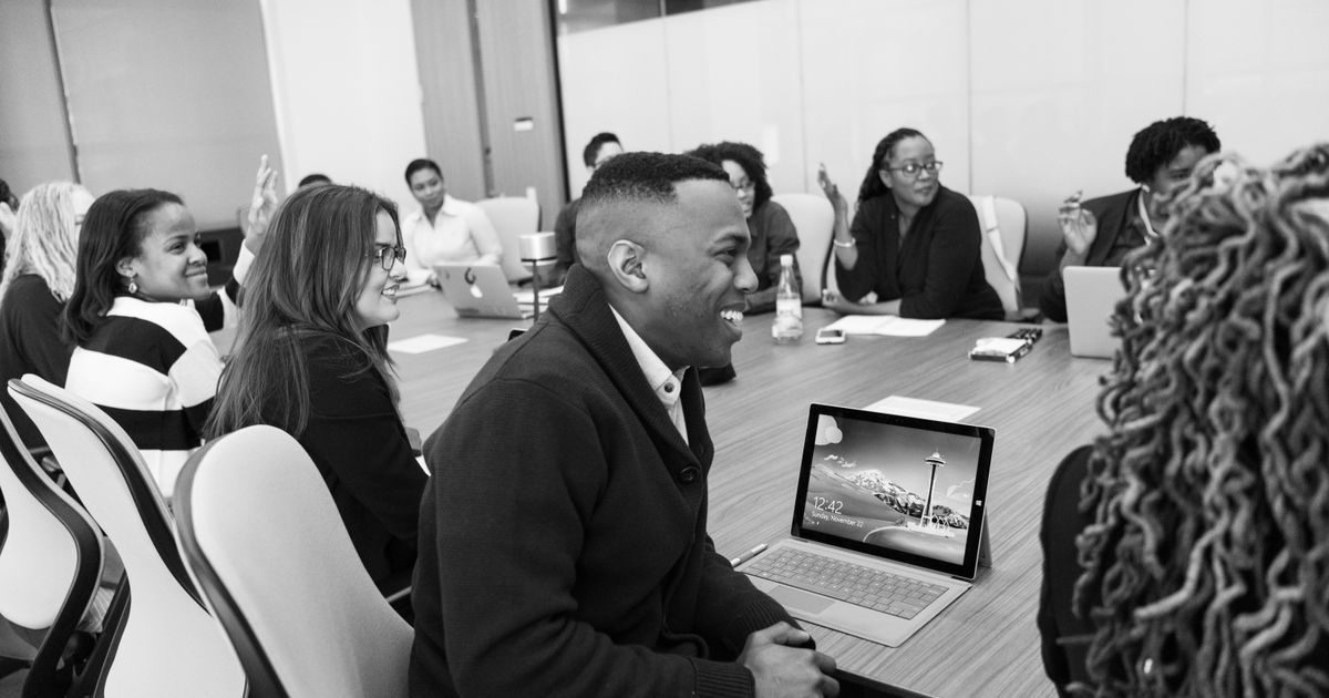Group of office workers laughing together at a conference table, illustrating relatable corporate humor