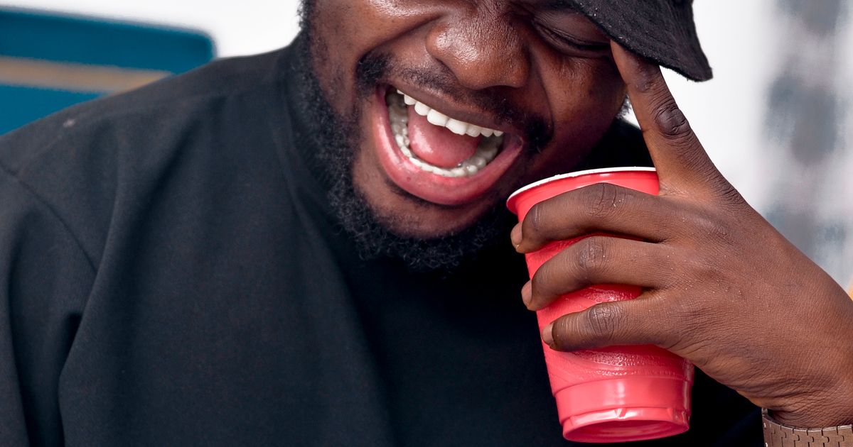 Person laughing while looking at their smartphone, scrolling through meme content on social media