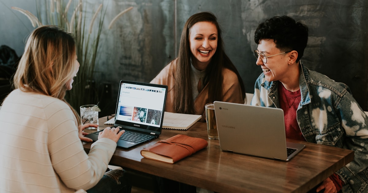 Group of people collaborating around a table with laptops
