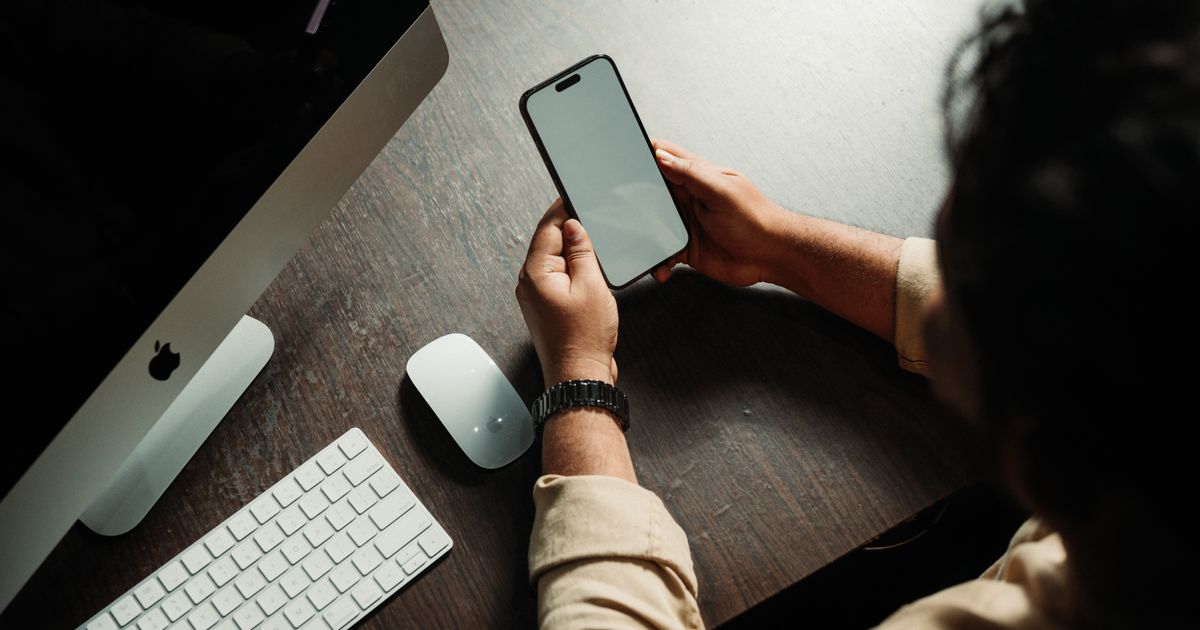 Person at a desk using a smartphone alongside a computer to research traffic channels